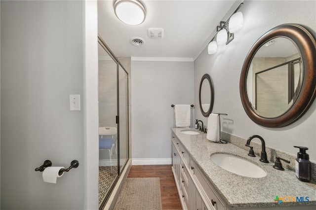 bathroom with crown molding, visible vents, a shower stall, and a sink