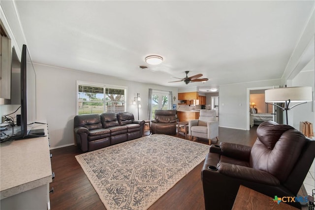 living room featuring baseboards, ceiling fan, and dark wood-style floors