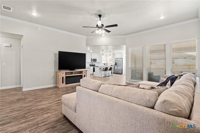 living room with wood-type flooring, ornamental molding, and ceiling fan