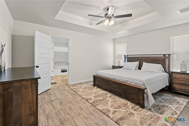 bedroom with crown molding, light hardwood / wood-style flooring, and a raised ceiling