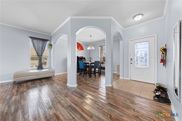 foyer with hardwood / wood-style flooring, ornamental molding, and an inviting chandelier