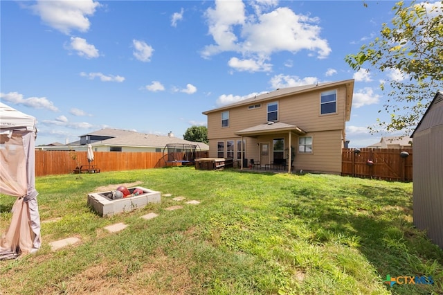 back of property with a fire pit, a jacuzzi, and a yard