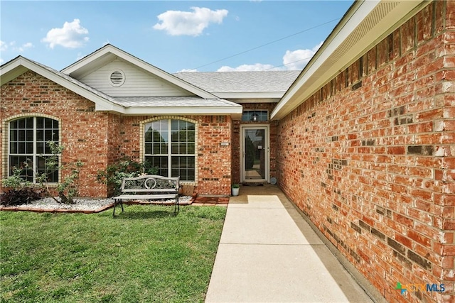 2606 Wesley Dr, Killeen, TX 76549 - view of exterior entry with brick siding, a yard, and roof with shingles