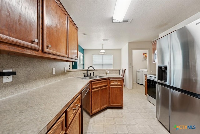 2606 Wesley Dr, Killeen, TX 76549 - kitchen featuring stainless steel appliances, washer and clothes dryer, brown cabinetry, light flooring, and backsplash
