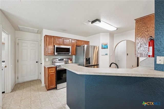 2606 Wesley Dr, Killeen, TX 76549 - kitchen featuring stainless steel appliances, brown cabinets, light countertops, a peninsula, and light floors