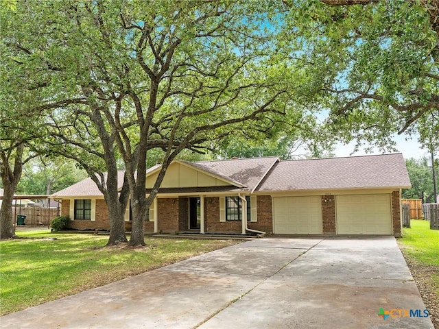 single story home featuring a front yard, brick siding, concrete driveway, an attached garage, and fence