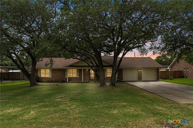 single story home featuring driveway, fence, a front lawn, brick siding, and a garage