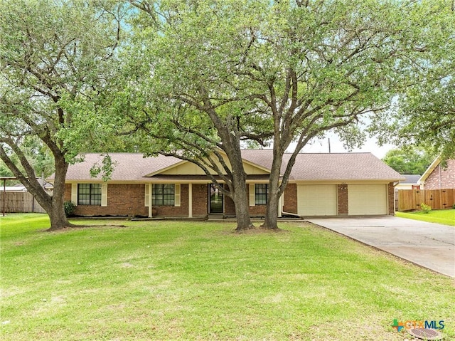 ranch-style house featuring driveway, a front yard, an attached garage, fence, and brick siding