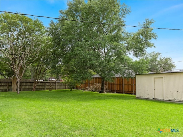 view of yard with an outdoor structure, a storage shed, and a fenced backyard