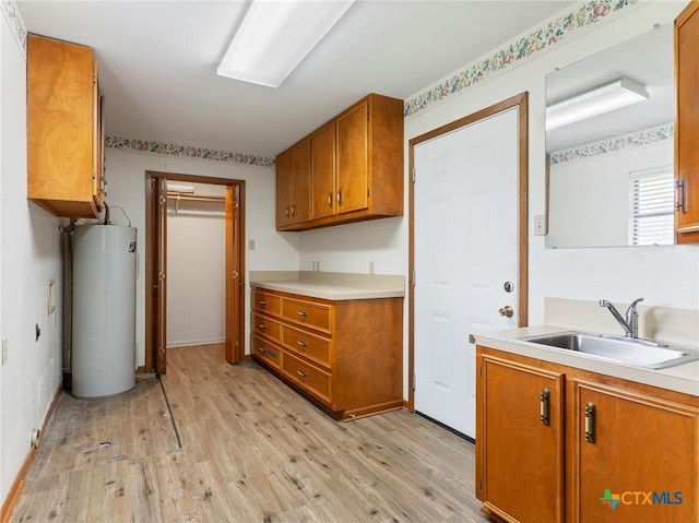 kitchen featuring brown cabinetry, water heater, light wood finished floors, and a sink