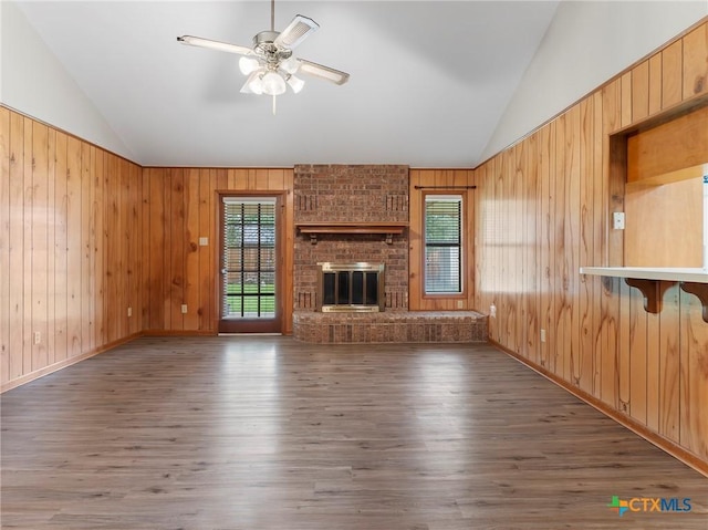 unfurnished living room featuring wood finished floors, wooden walls, and lofted ceiling