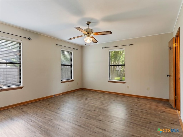 spare room with wood finished floors, ceiling fan, and baseboards