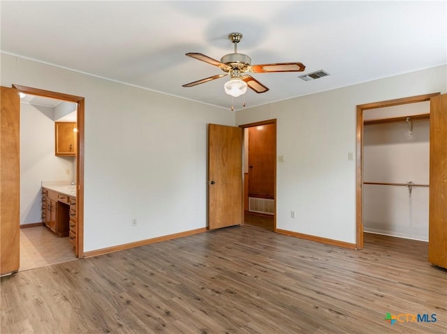 unfurnished bedroom with visible vents, light wood-type flooring, ensuite bathroom, and baseboards