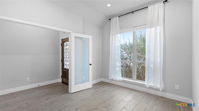 spare room featuring lofted ceiling, french doors, and light hardwood / wood-style flooring