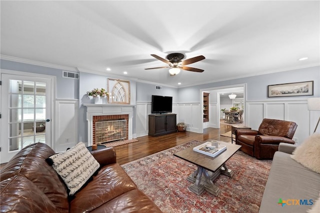 living room featuring a fireplace, ceiling fan, crown molding, and dark hardwood / wood-style floors