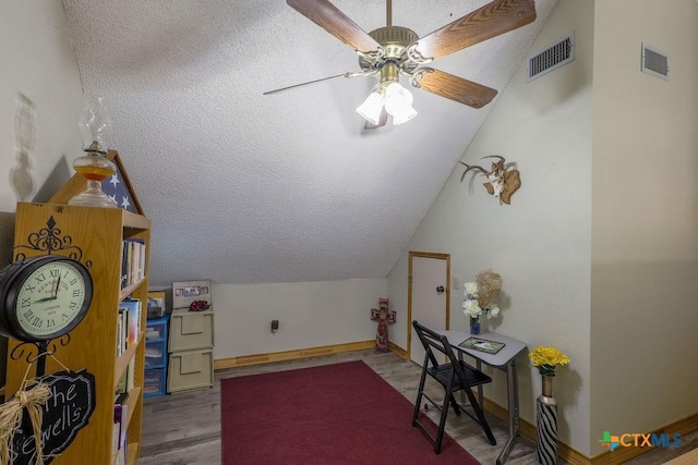 interior space with ceiling fan, hardwood / wood-style floors, lofted ceiling, and a textured ceiling