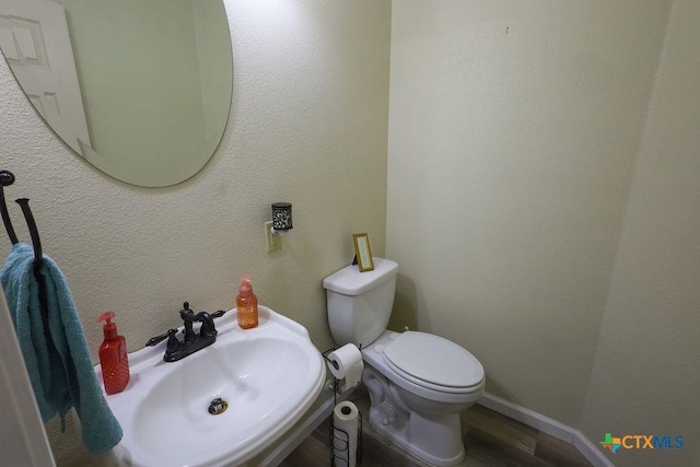 bathroom with toilet, hardwood / wood-style floors, and sink