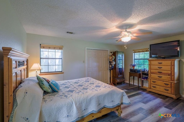 bedroom with ceiling fan, dark hardwood / wood-style flooring, a closet, and a textured ceiling