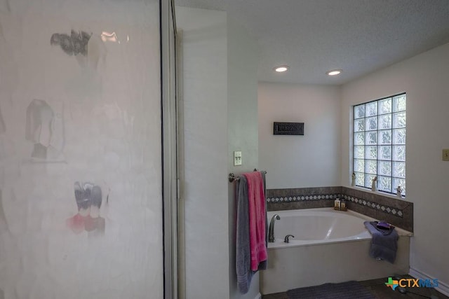 bathroom with a textured ceiling and a bath