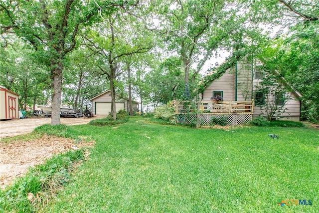 view of yard featuring a deck, a garage, and an outbuilding