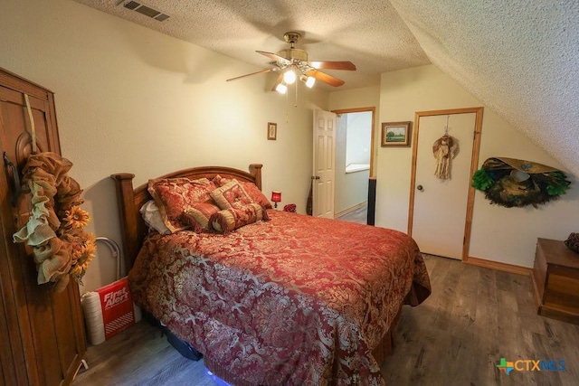 bedroom with vaulted ceiling, dark wood-type flooring, a textured ceiling, and ceiling fan