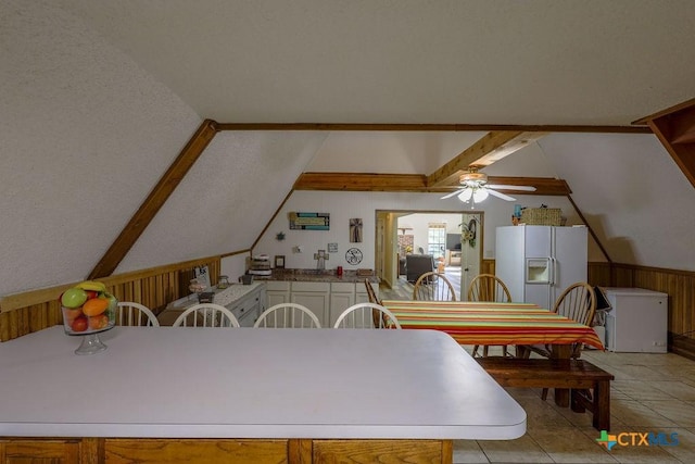 kitchen with white refrigerator with ice dispenser, light tile patterned floors, ceiling fan, and lofted ceiling with beams