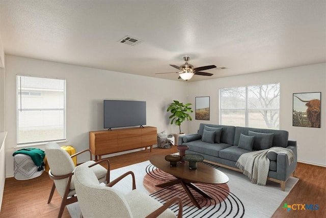 living room with ceiling fan, light hardwood / wood-style floors, and a textured ceiling