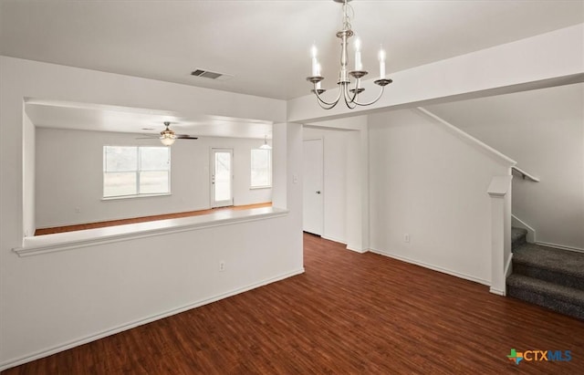 unfurnished living room with ceiling fan with notable chandelier and dark wood-type flooring