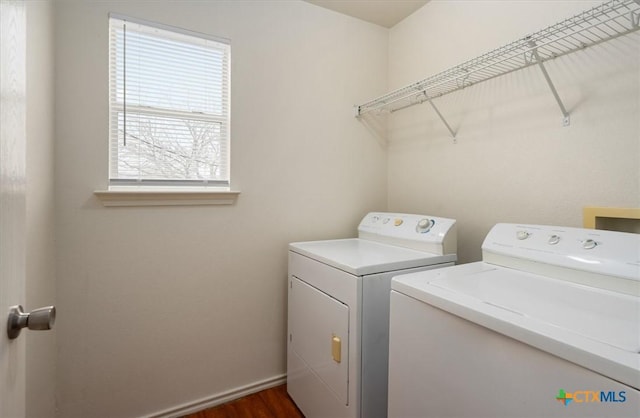 clothes washing area with dark wood-type flooring, a wealth of natural light, and washing machine and clothes dryer