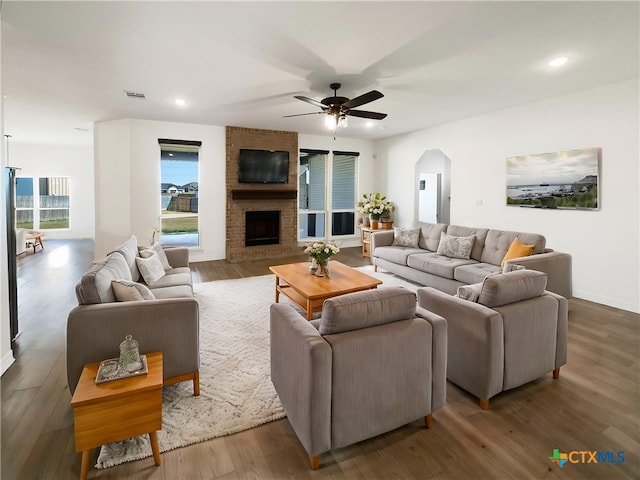 living room featuring a brick fireplace, hardwood / wood-style floors, and ceiling fan