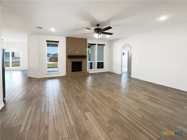 unfurnished living room featuring a brick fireplace, hardwood / wood-style floors, and ceiling fan