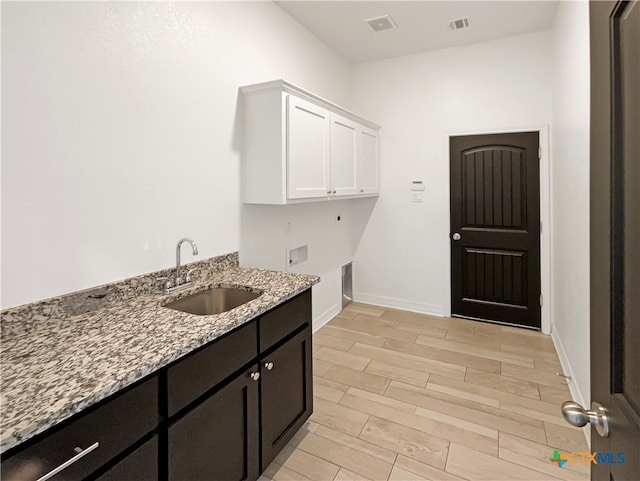 laundry area with hookup for a washing machine, cabinets, sink, electric dryer hookup, and light hardwood / wood-style flooring