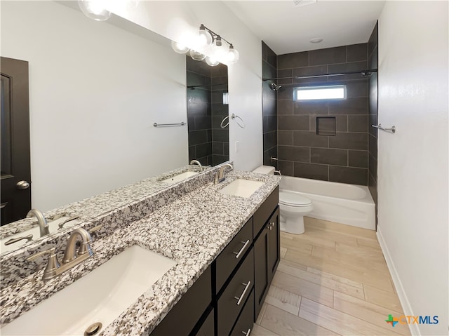 full bathroom featuring vanity, tiled shower / bath, and toilet