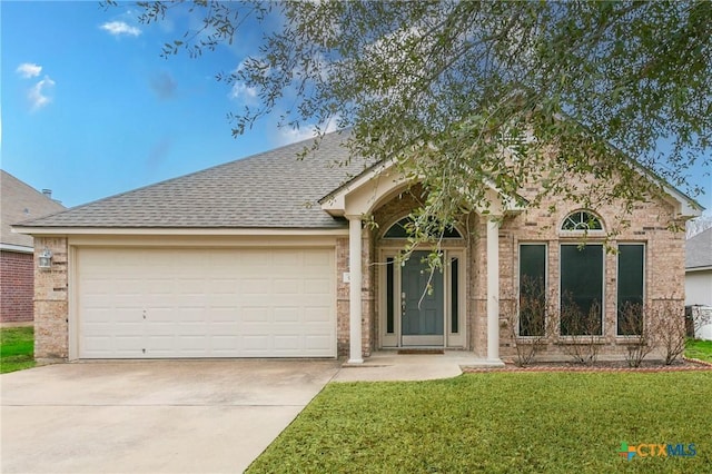 single story home featuring brick siding, a shingled roof, a front yard, a garage, and driveway