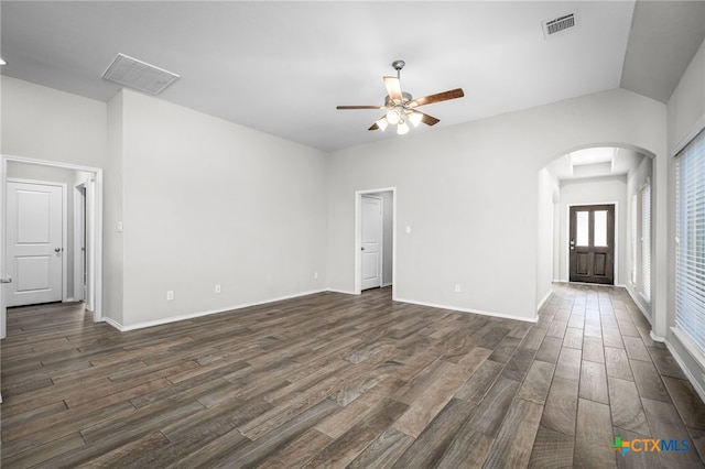 unfurnished living room with visible vents, arched walkways, dark wood-style flooring, and a ceiling fan