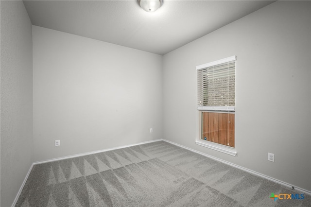 spare room with baseboards and carpet