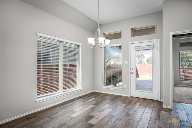 unfurnished dining area with baseboards, an inviting chandelier, and wood finished floors