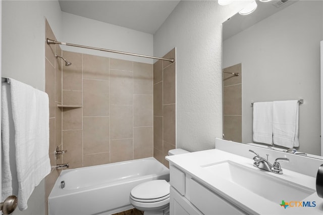 full bath with vanity, toilet, a textured wall, and shower / bathtub combination