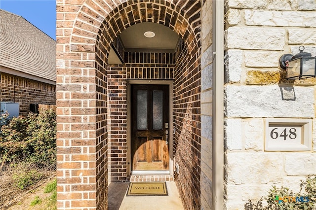 doorway to property with stone siding and brick siding