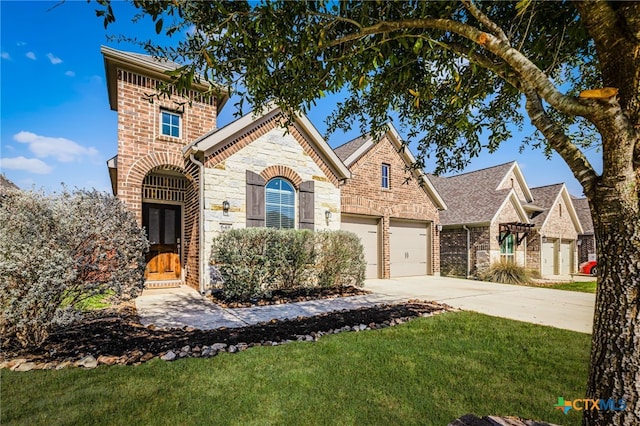 view of front of home featuring a front yard, driveway, an attached garage, stone siding, and brick siding