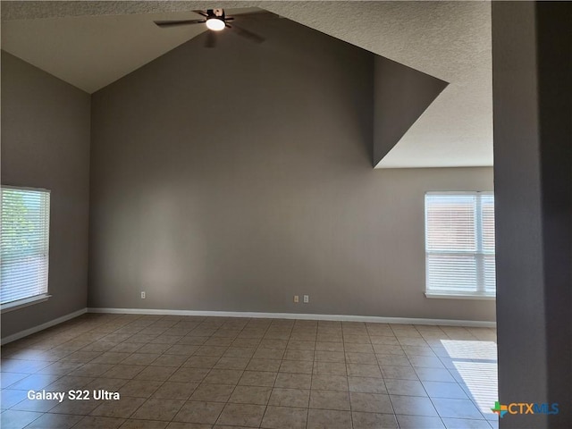 tiled spare room with vaulted ceiling, a ceiling fan, a textured ceiling, and baseboards