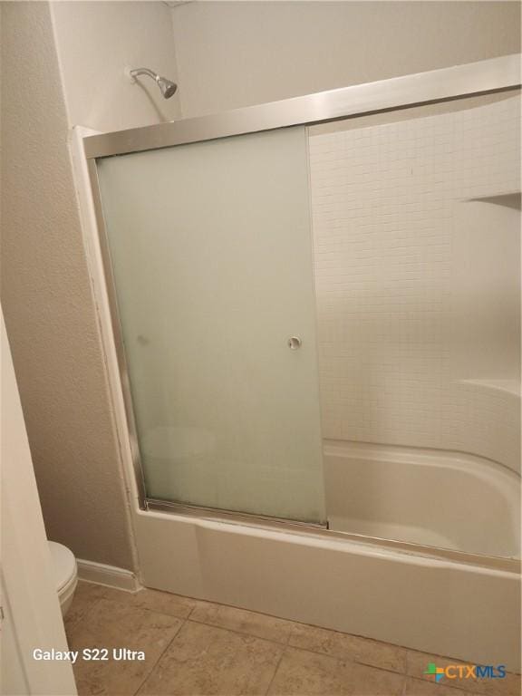 bathroom with tile patterned flooring, enclosed tub / shower combo, and toilet