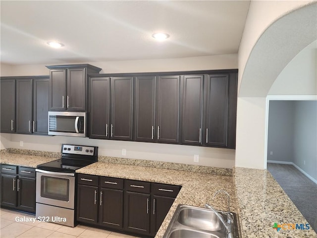 kitchen featuring a sink, light colored carpet, appliances with stainless steel finishes, light stone countertops, and recessed lighting
