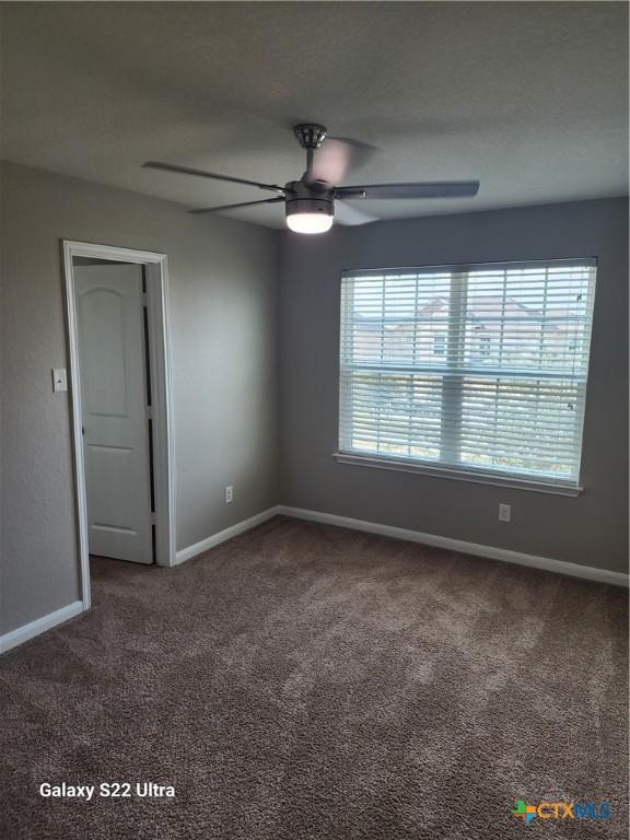 carpeted empty room featuring baseboards and ceiling fan