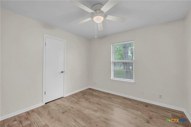 spare room featuring light wood-type flooring, baseboards, and ceiling fan