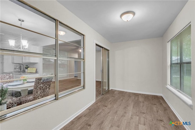spare room featuring baseboards, a notable chandelier, and wood finished floors