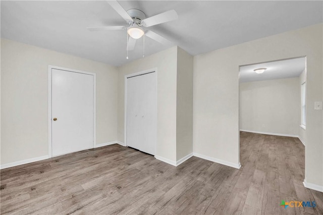 unfurnished bedroom with a closet, a ceiling fan, baseboards, and wood finished floors