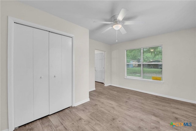 unfurnished bedroom with light wood-type flooring, baseboards, ceiling fan, and a closet