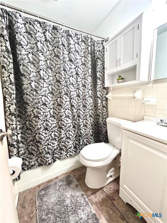 bathroom with shower / bath combo, toilet, tile patterned floors, vanity, and tile walls