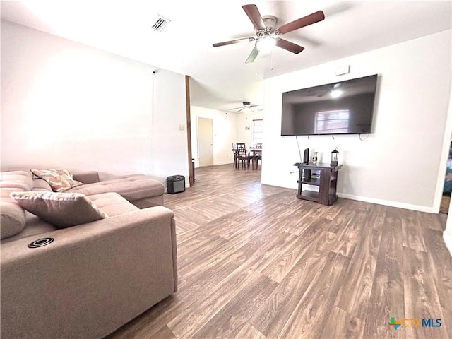 living area featuring a ceiling fan, wood finished floors, visible vents, and baseboards